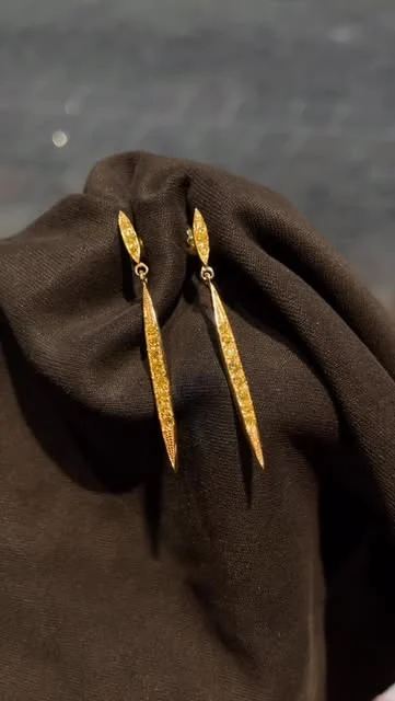 Paire de longues boucles d’oreilles dorées sur un tissu sombre
